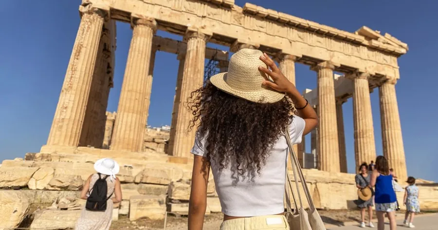 Eine Besucherin mit Strohhut blickt zu den Säulen des Parthenon hinauf